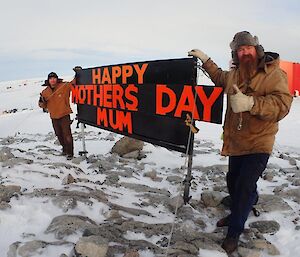 Expeditioners next to a sign outside in the snow reading ‘Happy Mother’s Day'