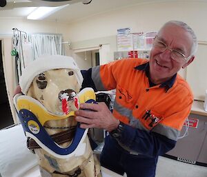 A plastic guide dog is bandaged by a male expeditioner in the clinic after a supposed boxing match
