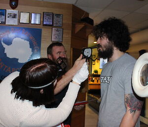 Expeditioner with thick, curly hair is having his beard judged