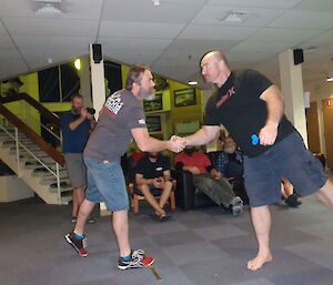 Two male dart players shake hands