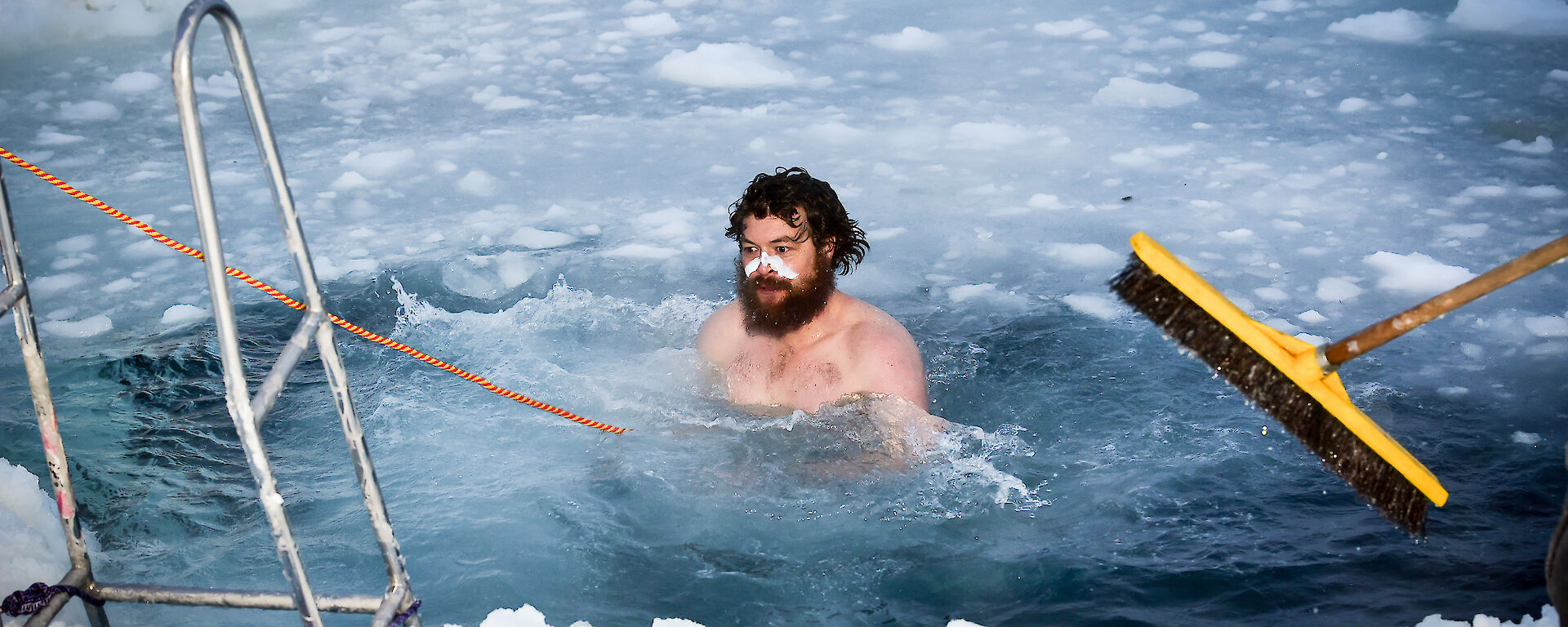 Expeditioner takes midwinter swim in a hole in the ice.