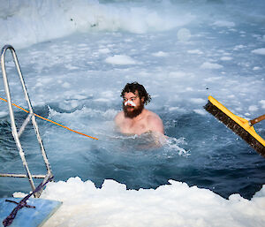 Expeditioner takes midwinter swim in a hole in the ice.