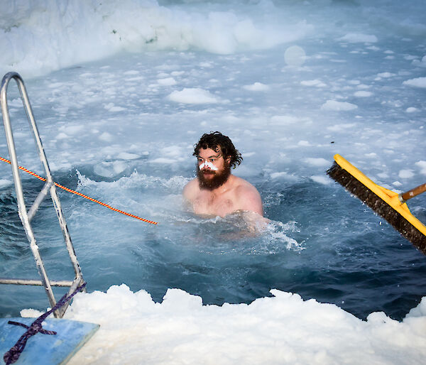 Expeditioner takes midwinter swim in a hole in the ice.