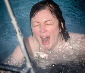 Female station doctor takes midwinter swim, but looks shocked as she surfaces.