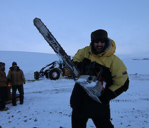 Expeditioner holds chainsaw up and smiles.