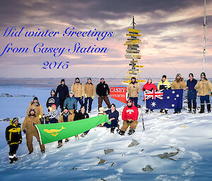 A group photo of the Casey station expeditioners at midwinter, outside near the famous Casey sign.