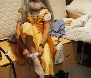 An older, bearded, male expeditioner is dressing up as Cinderella for a play.