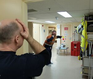 Expeditioner tests his eyesight, while a bearded male expeditioner points to some hazard signs.