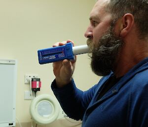 Expeditioner tests lung capacity on a machine where he is blowing into a tube.