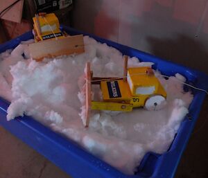 Toy diggers made by expeditioners rest atop ice in an esky.