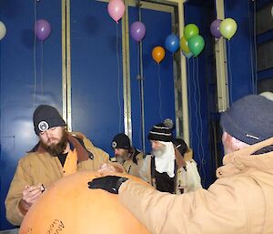 Expeditioner signs weather balloon, others mingle in the background.
