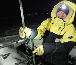 Expeditioner checks fuel levels with a dipstick in full gear, so little of his face is seen.