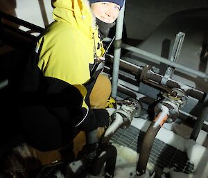 Female doctor switches levers on fuel tanks, outside in the dark with lights illuminating.