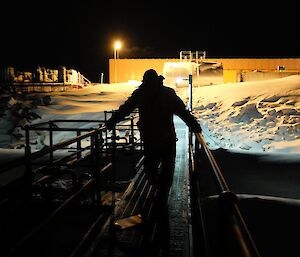 Expeditioner oversees refuel at night, and is silhouetted by lights at the station.