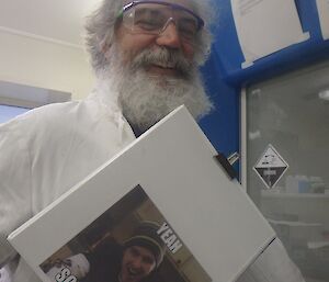 Expeditioner in white lab coat preparing samples, smiles for the camera.