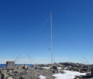 A tall antenna sits amongst rocks and snow