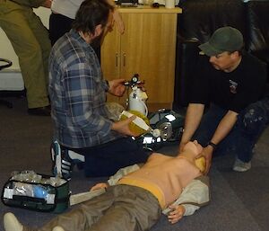 Woman attends to medical training dummy on floor