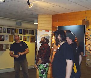 A group of male expeditioners are shown speaking to Mawson station via video link — the TV is not shown