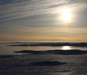 Looking across Shirley Channel and Shirley Island, under a bright sun, slightly hidden by light clouds.