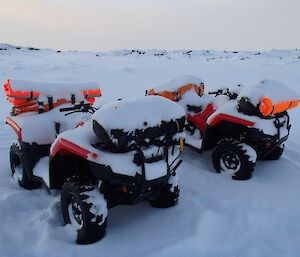 Two quad bikes covered in snow and ice