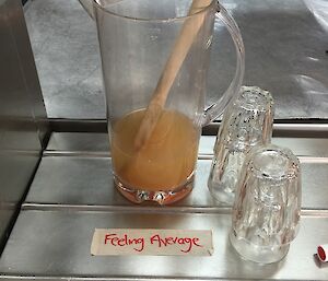 A pitcher of murky liquid with a large wooden spoon inside is preceded by tape that reads ‘Feeling average, lemon, honey, cayenne'