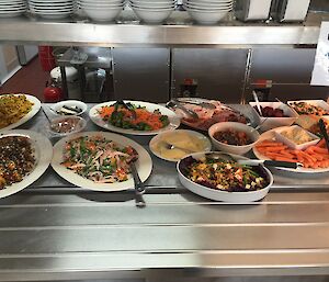 A buffet of healthy foods sits on a bain-marie ready to be served at lunchtime