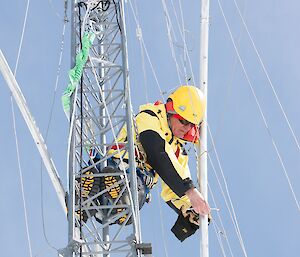 Expeditioner dangles in the scaffolding of a large aerial while doing repair work.