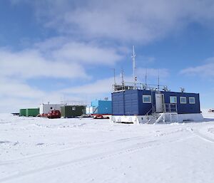 A neat row of buildings and vehicles set up alongside a ski landing area.