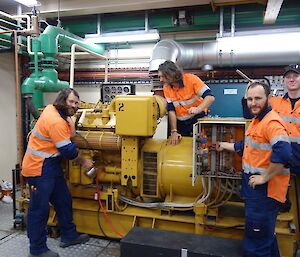 Four male electricians work around a large generator