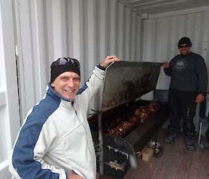 Expeditioners cooking a large roast on a spit roast BBQ.