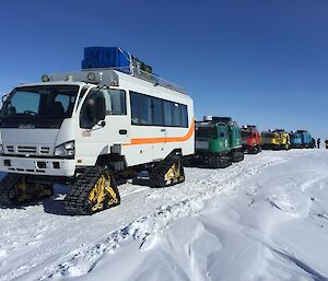 Five Hägglunds oversnow tracked vehicles in a row, all different colours, near the Wilkins runway