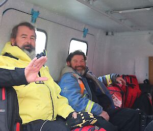 Two expeditioners in the back of a Hägglunds over snow vehicle ready to leave (one waving goodbye)