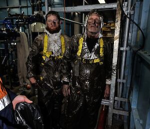 Jimmy and Jeff as they have exit one of the water tanks dressed in white coveralls that are mostly black with dirt and muck from carrying out tank cleaning work.