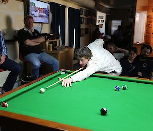 Mark leaning over the pool table to about to play his shot.