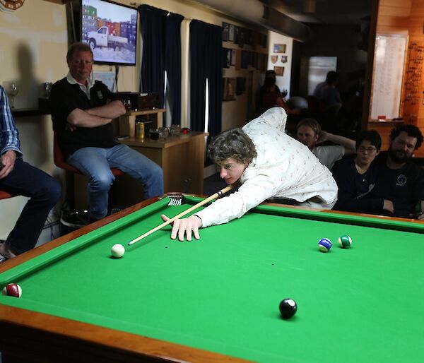 Mark leaning over the pool table to about to play his shot.