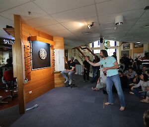 Mick preparing to throw a dart with the crowed watching on behind him.