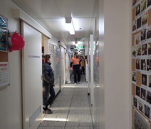 Sam walking along the passage looking into one of the many rooms with Donna standing in a closer doorway watching on