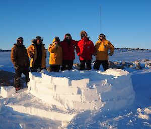 Six of seven construction crew standing behind a half built Igloo.