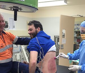 Training exercise in doctor’s clinic, with volunteer’s back being swabbed by surgeon