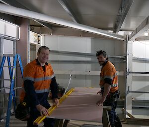 Dean and Tom prepare a sheet of plaster resting on saw stools ready for installation.
