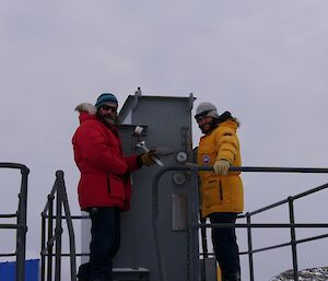 Mick and Andrew working on a high voltage transformer with Mick fitting a new gauge and Andrew watching.