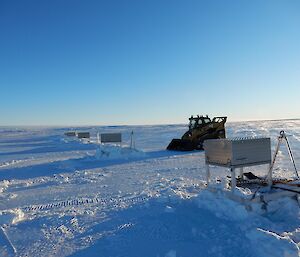 A small skid steer machine on the snow ready to push out the runway lighting sleds.