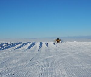 A D7 dozer pushing snow off in the distance on a blue ski day.