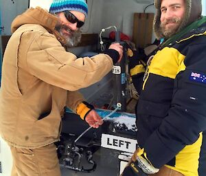 Two expeditioners at the back door of the blue Hagglund getting the water sampling gear out.