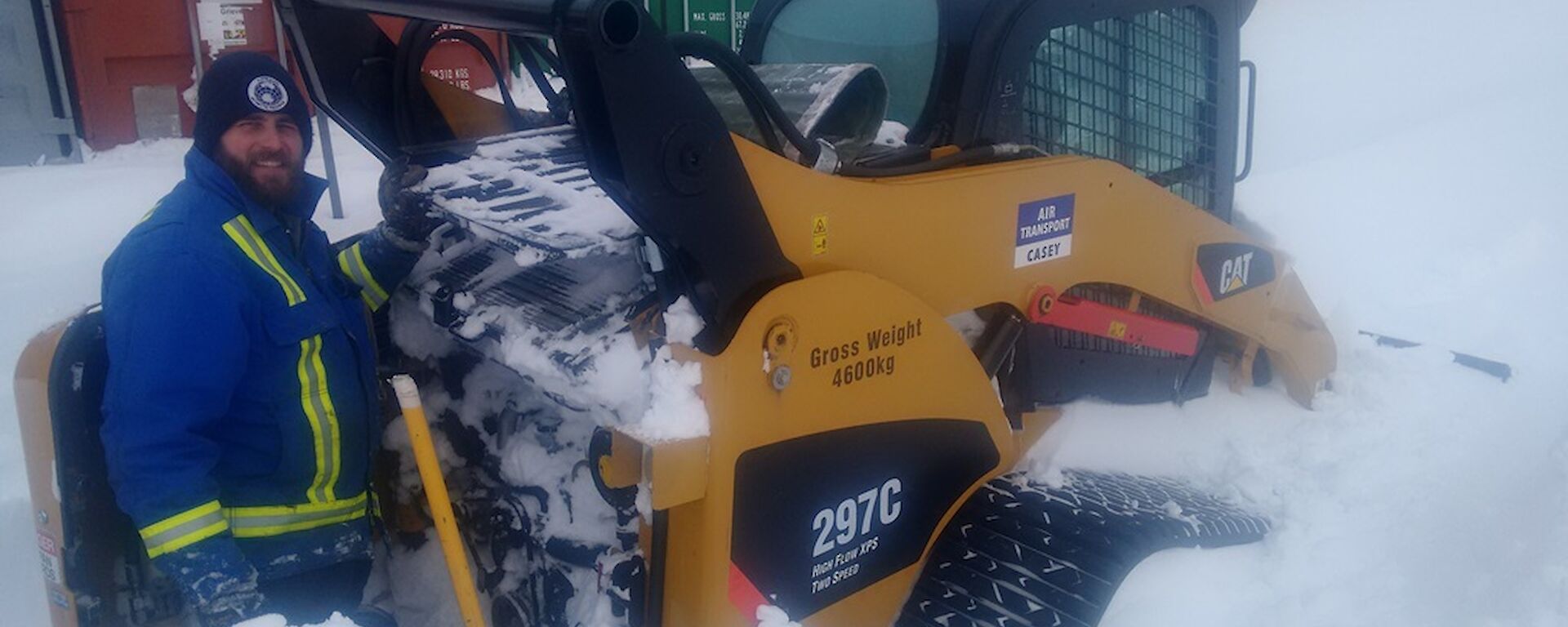 The senior mechanical supervisor digging out a skid steer machine that is almost buried in snow as well as the engine bay completely full of snow.