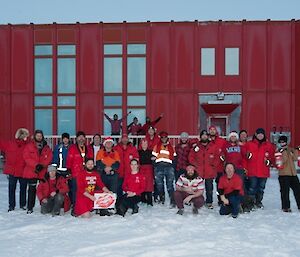 The Casey team dressed in red with a red Hagglund vehicle each side of the group all in front of the Red Shed.