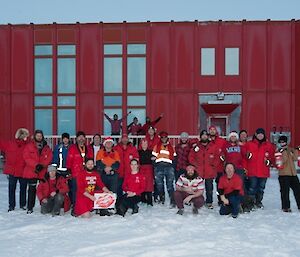 The Casey team dressed in red with a red Hagglund vehicle each side of the group all in front of the Red Shed.