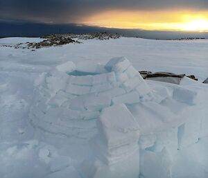 The igloo construction with spare blocks of ice next to it and a nice sun setting in the background.