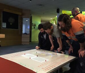 People gathering around as the footy tipping ladder is updated on the white board.