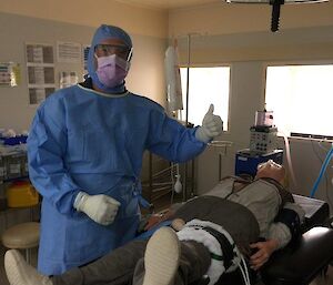 Cameron dressed in surgical clothing prepares Resusci-Ann for mock surgery on her ankle in a lay surgical assistant theatre scenario.